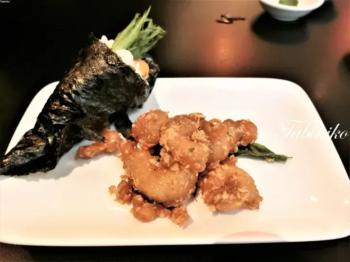 白い長方形の皿に盛られた揚げ物と海苔巻きご飯。