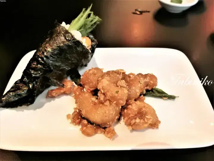 Fried food and seaweed-wrapped rice served on a white rectangular plate.