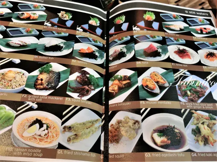 寿司や焼き魚、ラーメンなど様々な日本料理の写真と価格が記載された開かれたメニュー表。