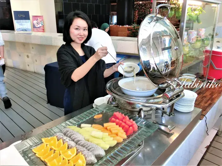 新鮮なフルーツが並ぶビュッフェの料理から女性がお皿に盛っている様子。