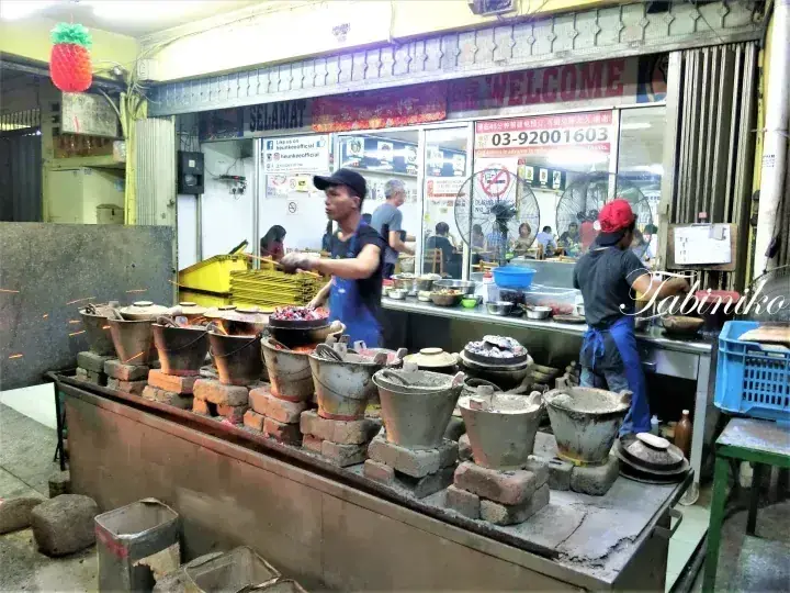 チャコールで伝統的な土鍋飯を調理するマレーシアの屋台のシェフたち。