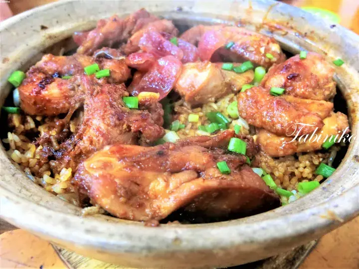 Claypot chicken rice with Chinese sausage and green onions in a traditional clay pot