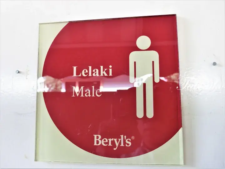 Red and cream square sign for Beryl’s men’s restroom featuring the word Lelaki and a male figure icon.