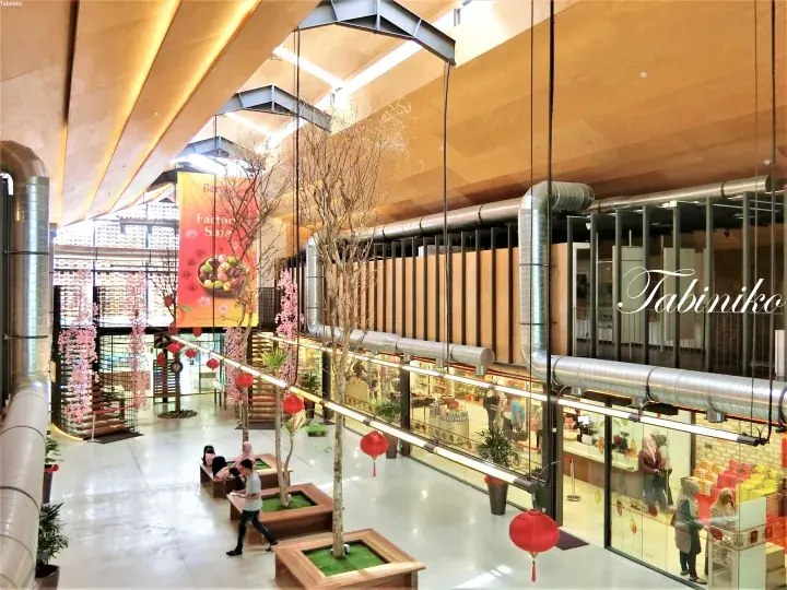 Interior view of The Exchange TRX featuring wooden ceilings, industrial ducts, and festive decorations in a modern shopping mall atrium.
