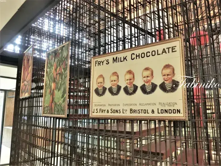 金属製の格子壁に掲げられた、5人の子供が描かれたヴィンテージのFry’s Milk Chocolateの看板。