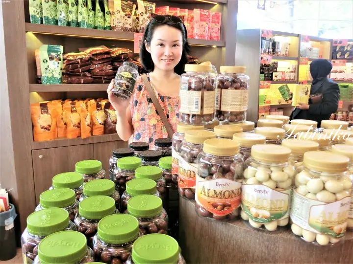 Woman holding a jar of Beryl’s chocolate in a store displaying Beryl’s Almond and other confectionery products.