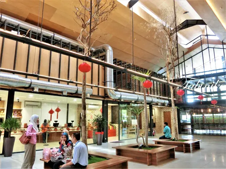 Modern interior of Tabanka featuring industrial design, hanging red lanterns, and wooden seating areas.