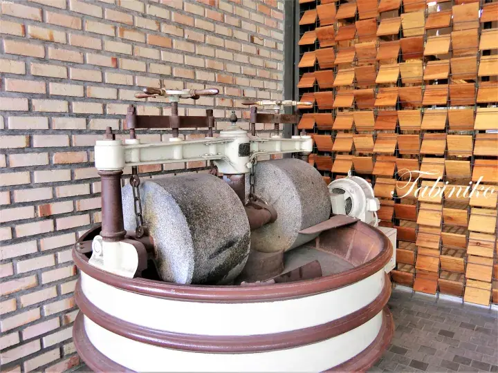 Vintage stone mill with large grinding wheels inside a brick building, showcasing traditional food processing heritage.