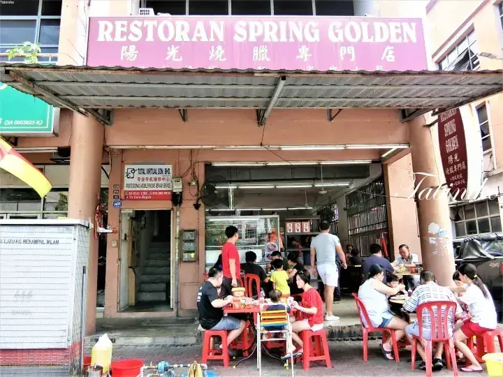 マレーシアの「Restoran Spring Golden」で、屋外テーブルで食事をする客たちの様子。