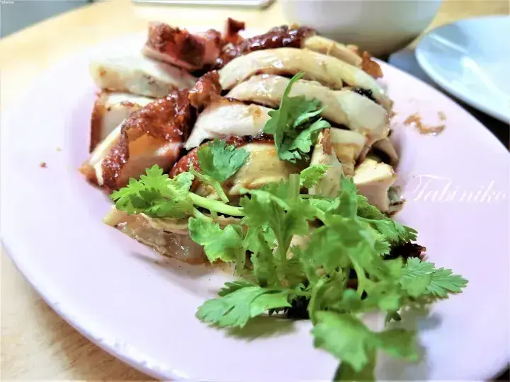 新鮮なパクチーを添えた、マレーシアの定番料理であるローストチキンと白鳥鶏の盛り合わせ。