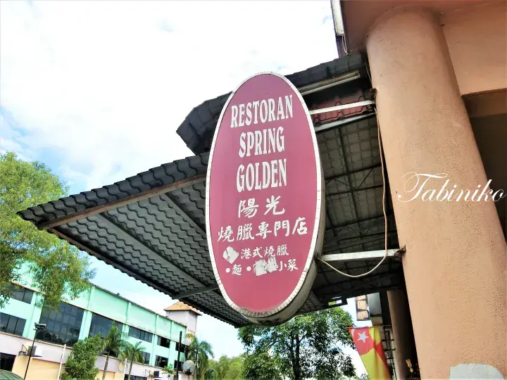 Red oval sign for Restoran Spring Golden featuring Chinese characters and menu items like roast meat.