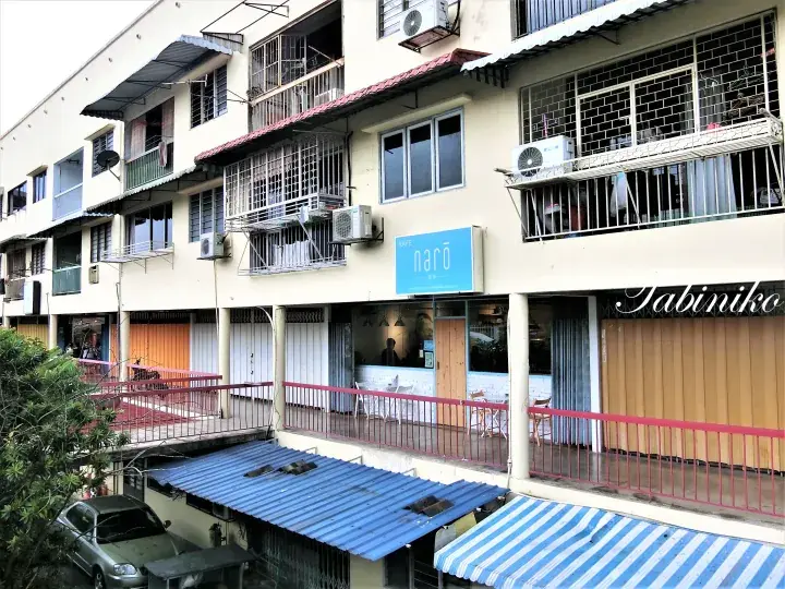 Street view of a shophouse building featuring narō cafe and Jabiniko restaurant with air conditioning units and metal grilles.