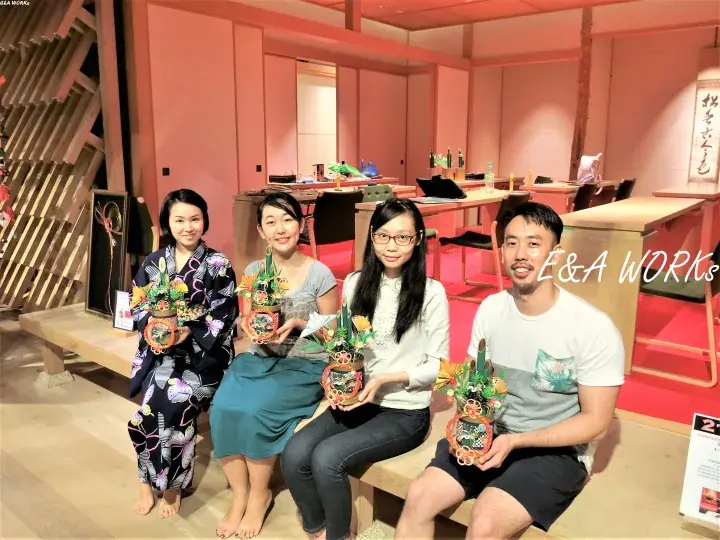 Four people holding handmade crafts at E&A Works, a Japanese cultural experience venue.