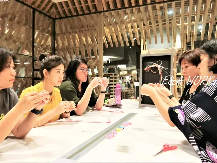 Women participating in a crafting workshop at E&A Workshop, focusing on making decorative items at a long table.