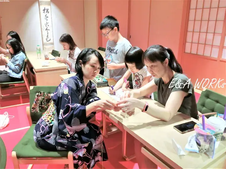 Visitors in yukata participate in a traditional craft workshop at a cultural venue.