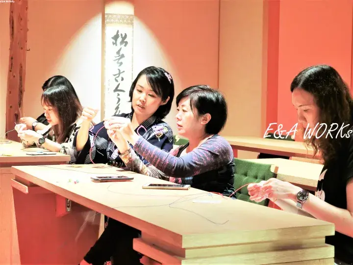 Women participating in a jewelry-making workshop at E&A Works, focusing on crafting beads and wire.