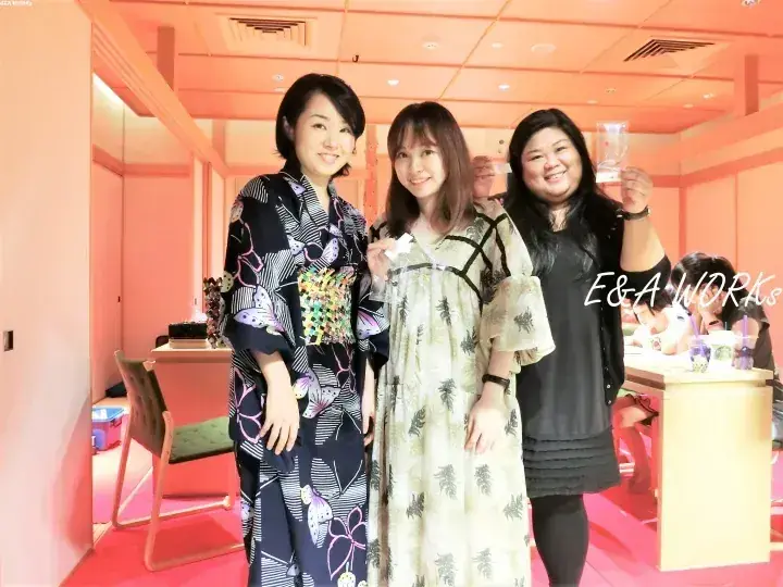 和服を着た女性を含む3人の女性が、イベント会場で一緒にポーズをとっている。