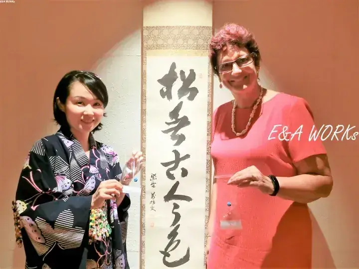 E&A Worksのイベントで書道の掛け軸を手にする二人の女性。