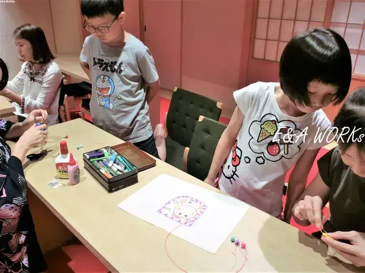 温かみのある部屋で、子供たちが木製のテーブルで工作を楽しんでいる様子。