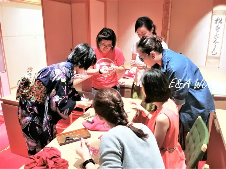 Women gather around a table for a traditional Japanese craft workshop, with one participant wearing a patterned kimono.