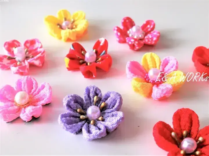 E&A WORKSによる、真珠の中心を持つカラフルな手作り布の花のコレクション。