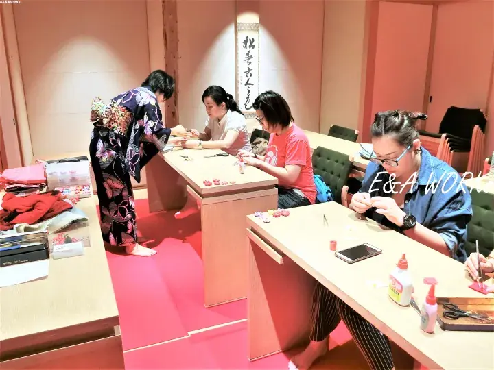 Women in a workshop making traditional crafts, with one person wearing a floral kimono.