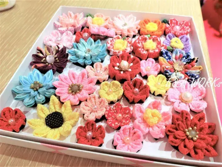 真珠の芯が付いたカラフルな手作り布花が白い箱に整然と並んでいる。