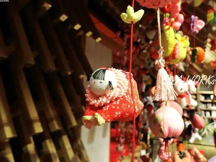 Colorful handmade fabric dolls hanging as decorations in a traditional wooden shop interior.