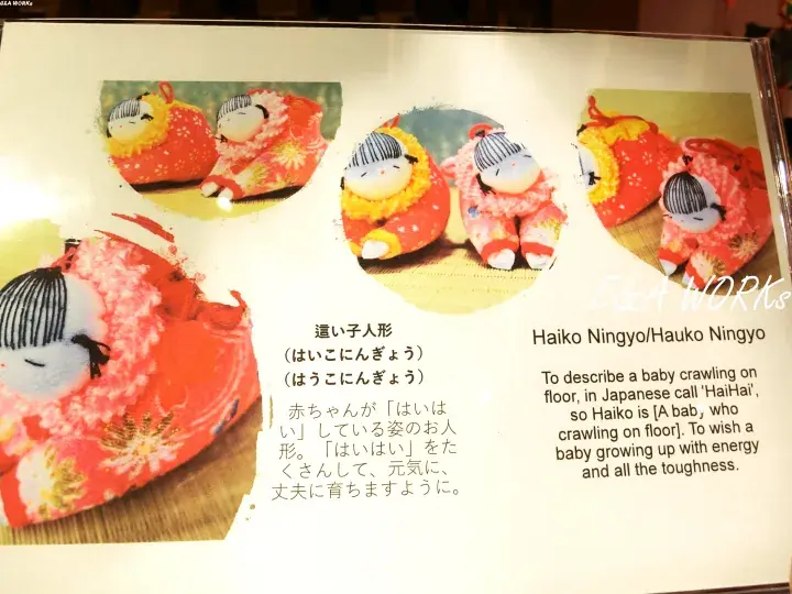 Haiko Ningyo dolls displayed with Japanese and English text explaining their meaning as symbols of healthy baby growth.