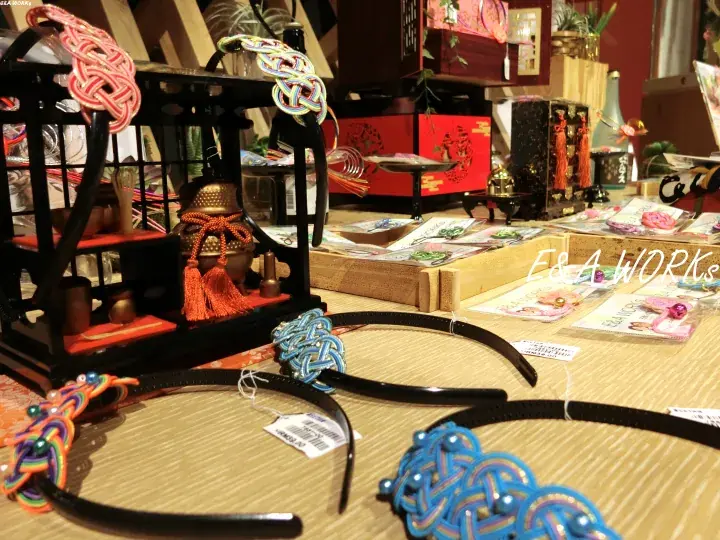 Colorful Chinese knot headbands displayed on a table alongside traditional decorative items and crafts.