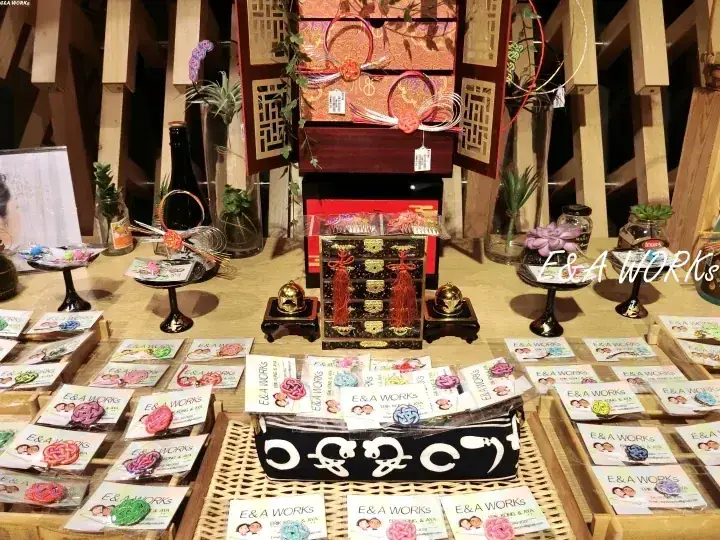 E&A WORKSの手作りアクセサリーが木製のブースで展示され、背景には伝統的な中国ランタンが見える。