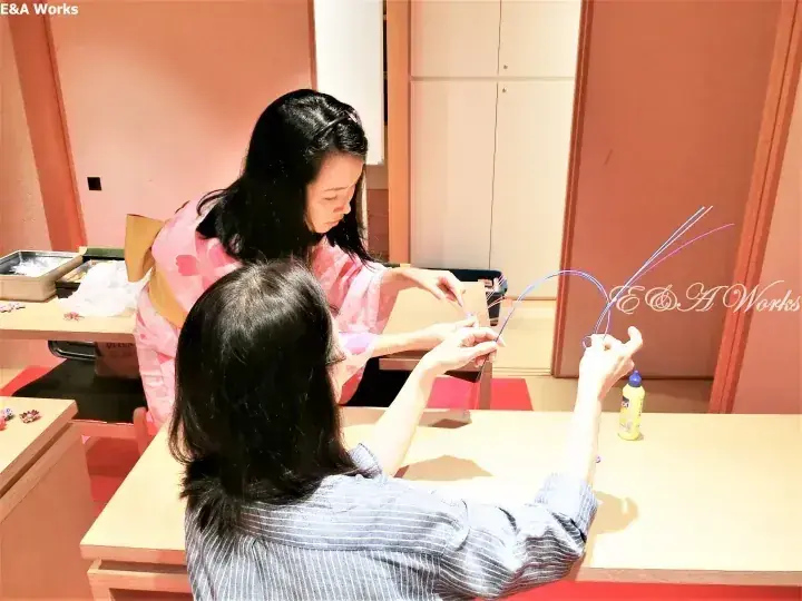 兩位女性在溫馨的室內環境中,坐在桌前專注地製作精緻的金屬絲工藝品。