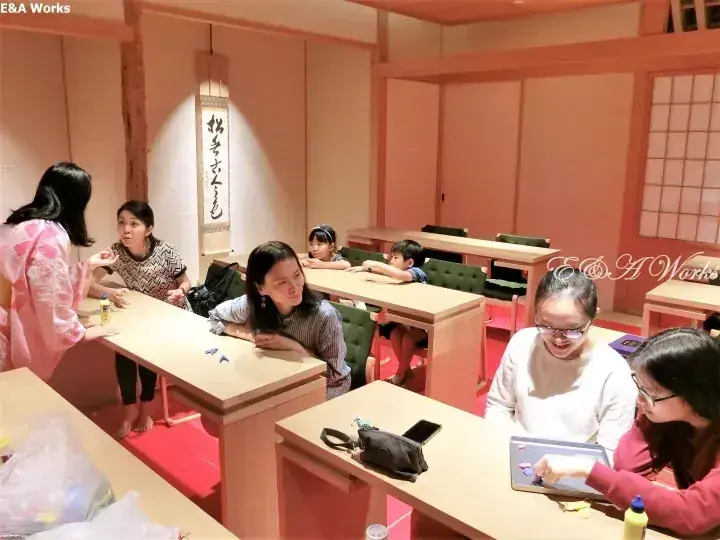 客人與兒童在鋪有榻榻米與木製傢俱的房間內參加日本傳統工藝工作坊。