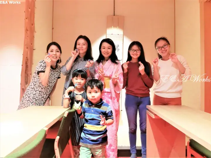 Group of adults and children posing happily inside a modern property space with warm lighting.