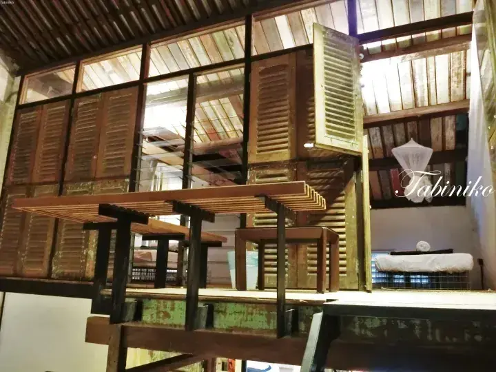 Interior of Tabiniko featuring rustic wooden shutters, exposed beams, and a cozy bed setup.