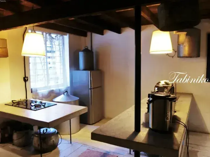 Cozy kitchen with wooden beams, a gas stove, and a refrigerator, featuring a Tabiniko watermark.