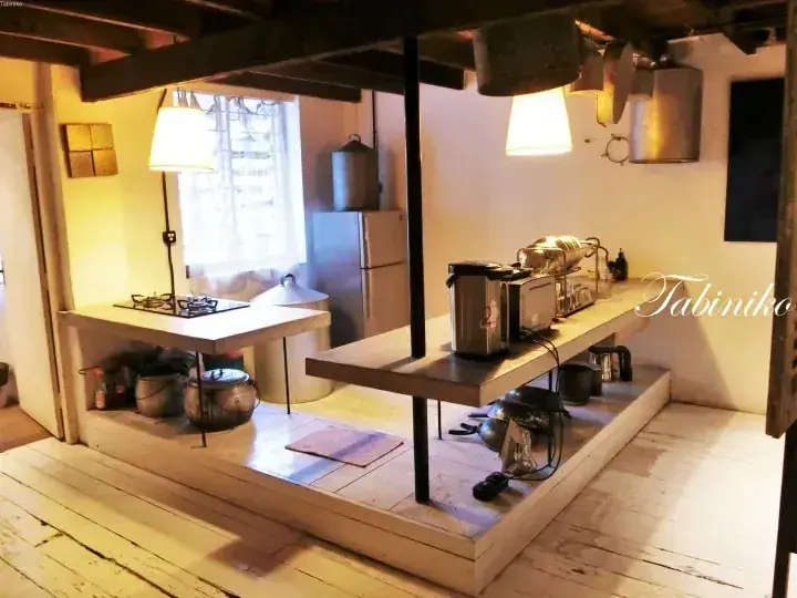 Cozy rustic kitchen with wooden beams, open shelving, and vintage appliances in a warm, natural setting.