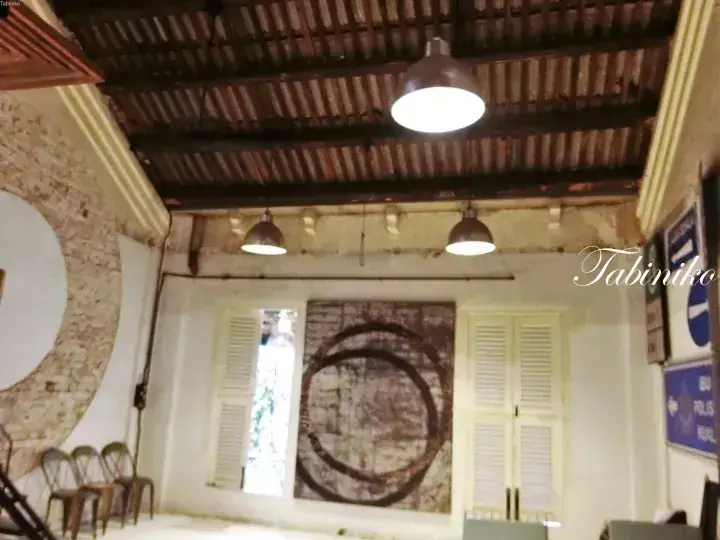 Interior of a heritage building with exposed brick walls, corrugated metal ceiling, and vintage industrial pendant lights.