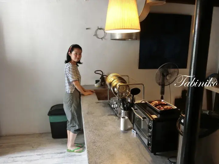 食器棚やトースターオーブンが並ぶモダンなキッチンでカウンターに寄りかかる女性。