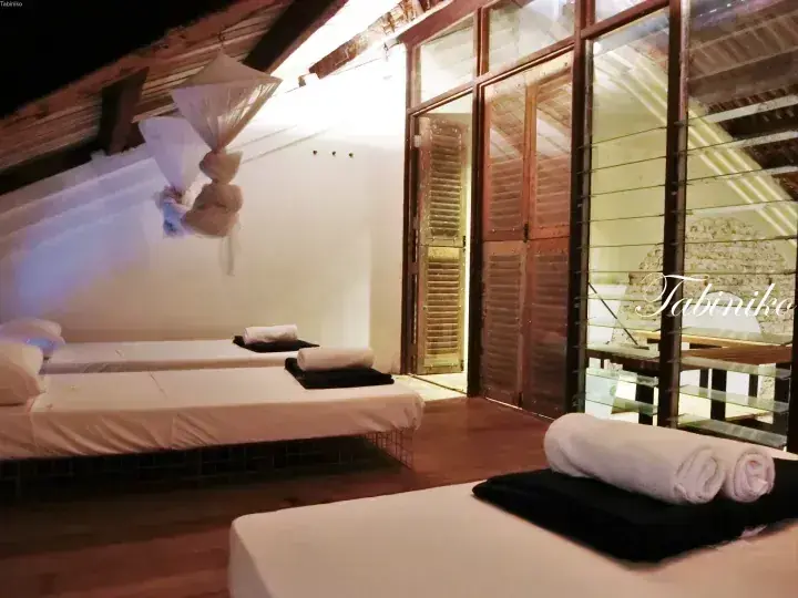 Cozy attic room with wooden floors, white daybeds, and glass doors leading to a balcony at a boutique property.