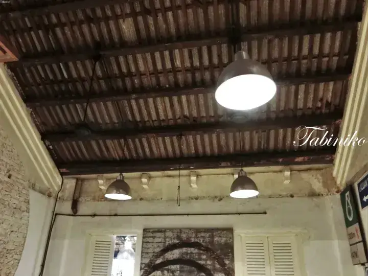 Rustic ceiling with corrugated metal sheets and vintage pendant lights at Tabiniko.