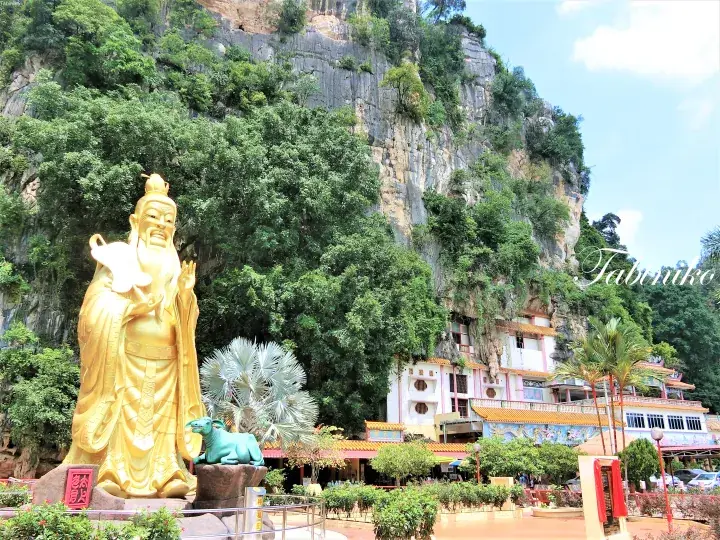 マレーシアの寺院にある金色の神像と石灰岩の崖。