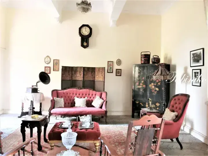 Vintage living room with pink velvet sofa, antique cabinet, and gramophone in a heritage property.
