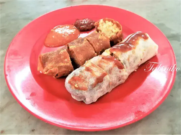 Fried banana rolls with sweet and spicy sauces served on a red plate.