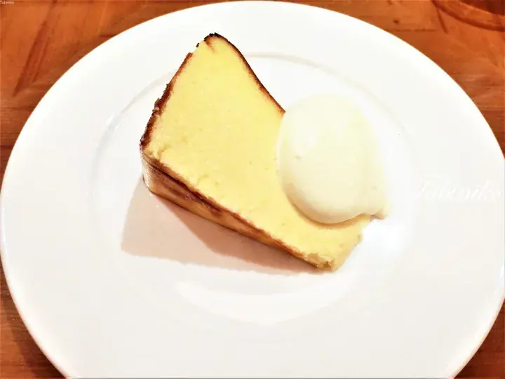 白い皿の上に盛られた、クリーミーなチーズケーキの切り身とバニラアイスクリーム。