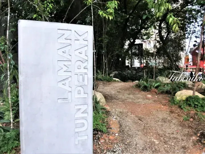 Stone sign reading LAMAN TUN PERAK at the entrance to a lush garden path.