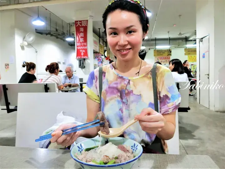 大眼海南茶室で海南鶏飯を前に笑顔で箸とスプーンを持つ女性。