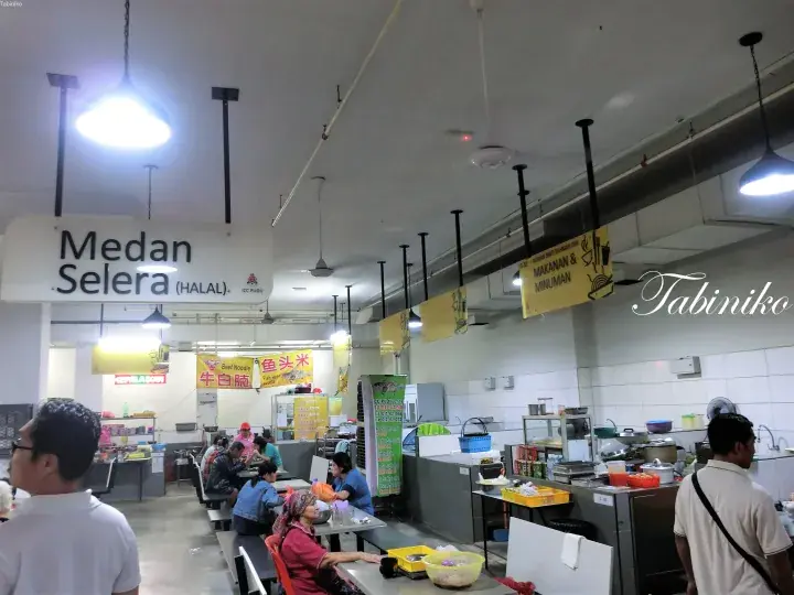 客席で食事をする人々と屋台が見えるMedan Seleraフードコートの内観。
