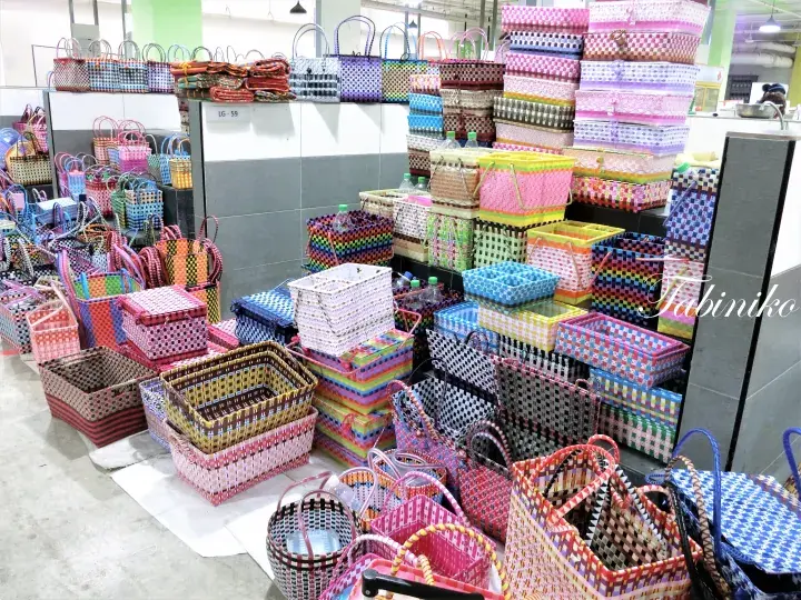 鮮やかな色と幾何学模様の編み込みバスケットやバッグが店内に積み上げられた商品陳列。
