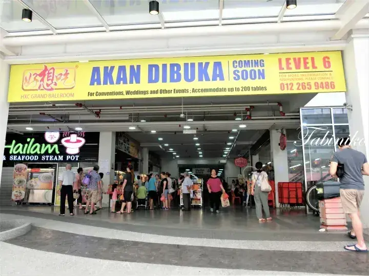 Crowd of people queuing outside a food court entrance under a large yellow banner advertising HXC Grand Ball Room on Level 6.